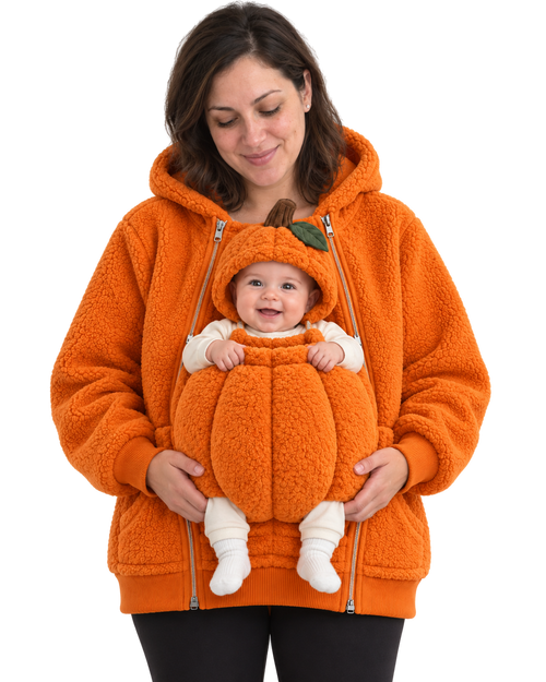 Mom wearing the orange Pumpkin hoodie. Baby sits in the front pouch wearing the matching pumpkin hood with stem and leaf, both socked feet showing.